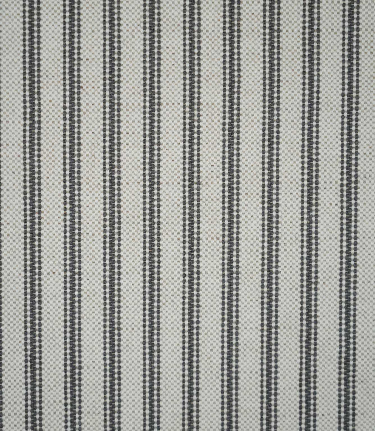 Grey ticking stripe fabric with evenly spaced charcoal grey woven stripes on a natural cream background, showing the classic striped design and textured weave.