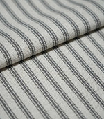 Folded grey ticking stripe fabric showing the repeating charcoal grey striped design and textured natural cream weave.