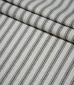 Layered folds of grey ticking stripe fabric, highlighting the evenly spaced charcoal stripes and tactile woven texture.