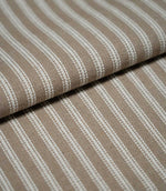 Folded natural ticking stripe fabric showing the repeating ivory striped design and textured taupe-beige woven finish.