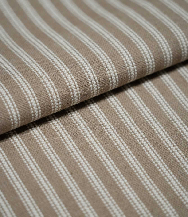 Folded natural ticking stripe fabric showing the repeating ivory striped design and textured taupe-beige woven finish.
