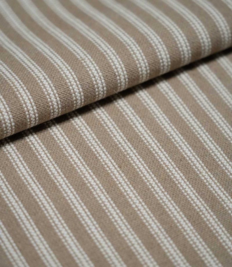Close-up of natural ticking stripe fabric arranged in a soft fold, highlighting the fine ivory stripes and subtle woven texture.