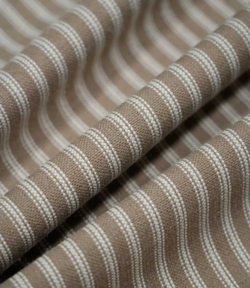 Natural ticking stripe fabric arranged in soft flowing folds, showing how the ivory striped pattern follows the drape of the textured weave.