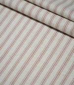 Layered folds of pink ticking stripe fabric with narrow dusty pink woven stripes on a cream background, highlighting the fabric’s texture and repeating pattern.