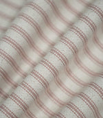 Pink ticking stripe fabric arranged in soft flowing folds, showing the dusty pink woven stripes, cream background and natural drape of the fabric.