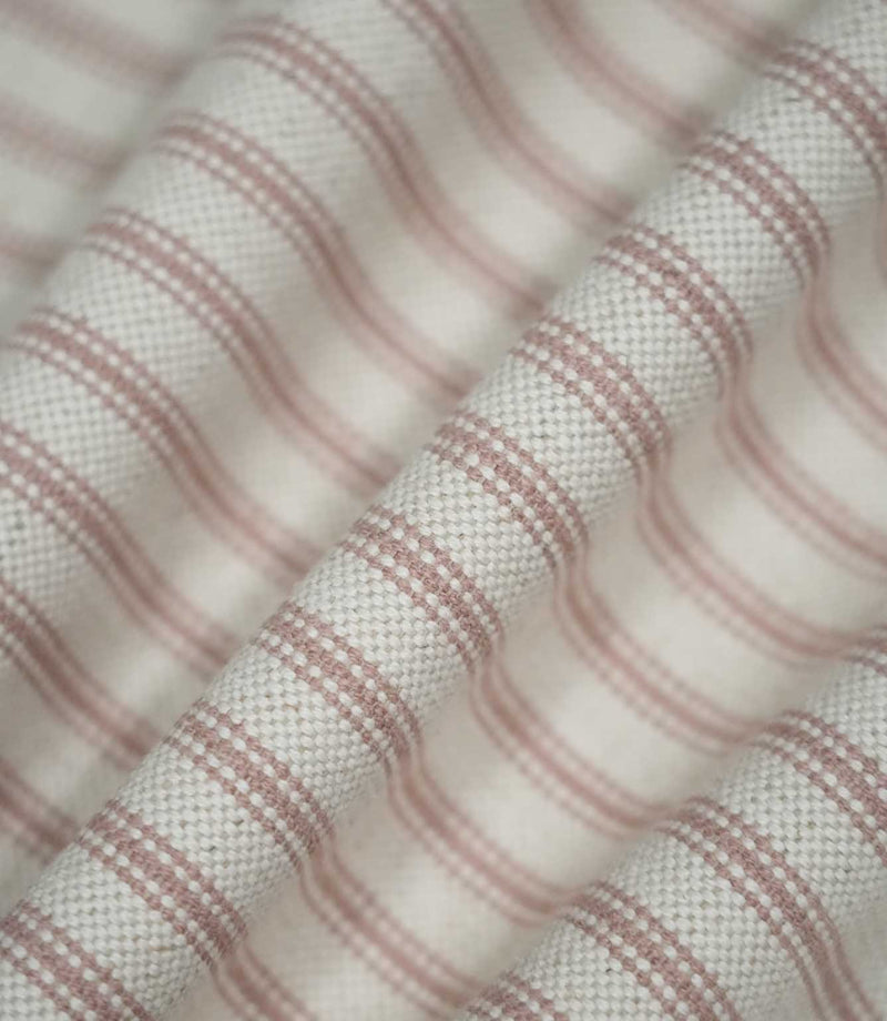 Pink ticking stripe fabric arranged in soft flowing folds, showing the dusty pink woven stripes, cream background and natural drape of the fabric.