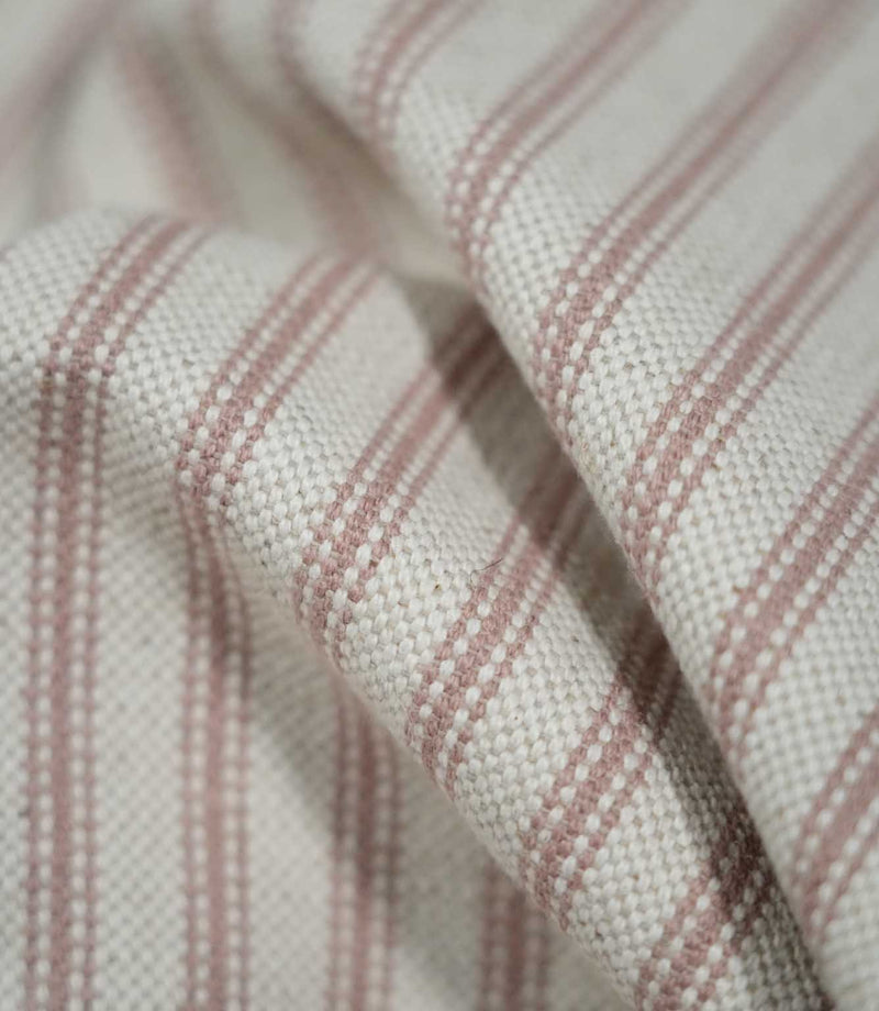 Detailed close-up of draped pink ticking stripe fabric, highlighting the dusty pink stripes, cream woven ground and tactile textured finish.