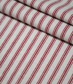 Layered folds of red ticking stripe fabric with evenly spaced red woven stripes on a natural cream background, highlighting the fabric texture and pattern.