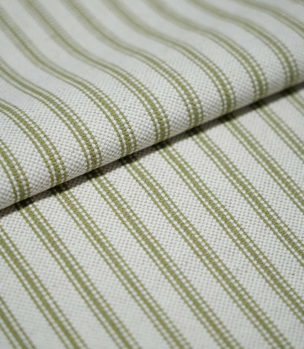 Folded sage green ticking stripe fabric showing the repeating narrow stripes and textured cream weave in close detail.