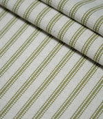 Layered folds of sage green ticking stripe fabric with evenly spaced woven stripes on a natural cream background, highlighting the fabric texture and pattern.