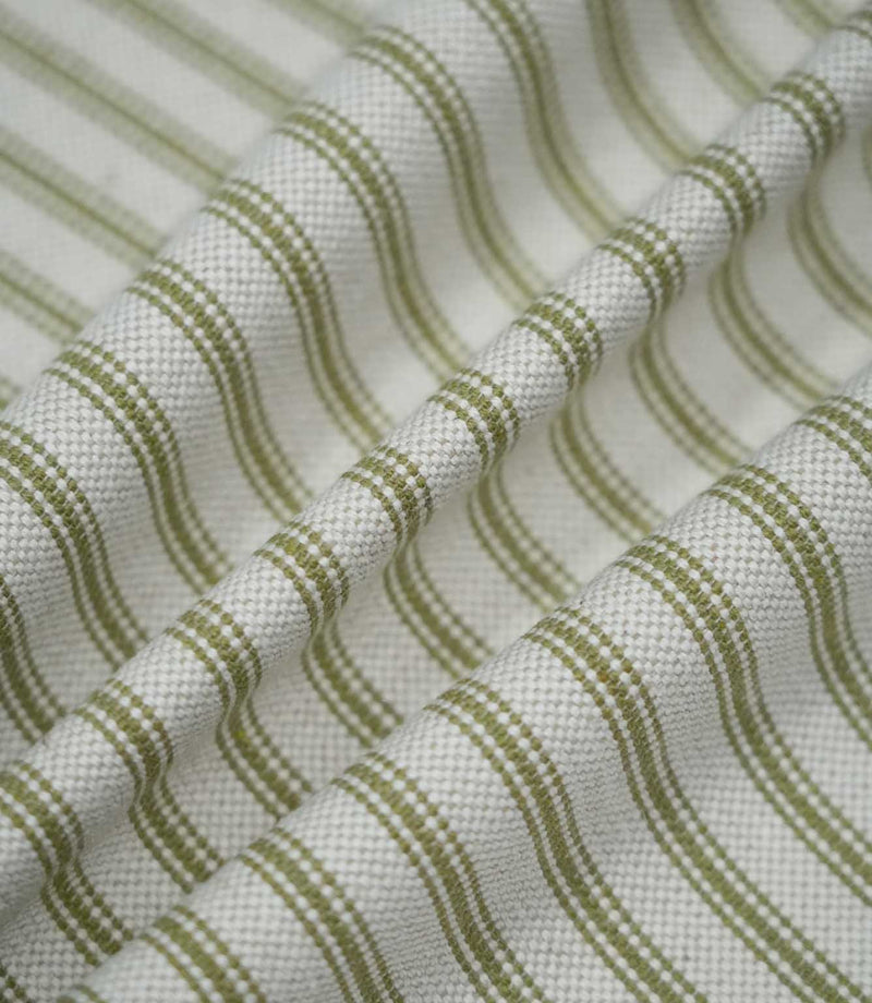 Sage green ticking stripe fabric arranged in soft flowing folds, showing the repeating green stripes, natural cream ground and textured woven finish.