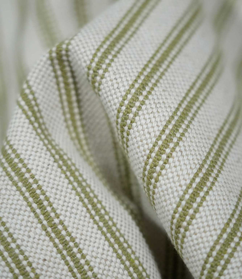 Detailed close-up of draped sage green ticking stripe fabric, highlighting the narrow woven stripes, natural cream background and tactile textured weave.