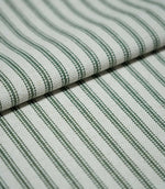 Folded sap green ticking stripe fabric showing the repeating dark green stripes and natural cream woven texture in close detail.