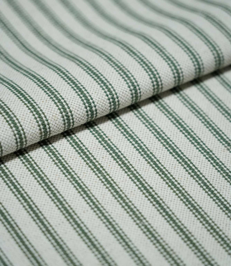 Folded sap green ticking stripe fabric showing the repeating dark green stripes and natural cream woven texture in close detail.
