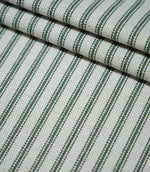 Layered folds of sap green ticking stripe fabric with evenly spaced dark green stripes on a natural cream background, highlighting the woven texture.