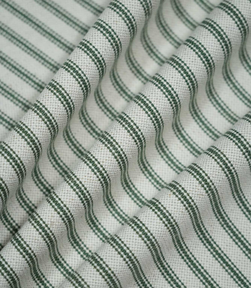 Sap green ticking stripe fabric arranged in soft flowing folds, showing the repeating dark green stripes, natural cream ground and tactile woven finish.