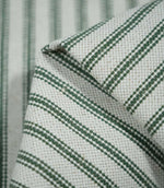 Detailed close-up of folded sap green ticking stripe fabric, highlighting the dark green woven stripes, natural cream background and textured weave.