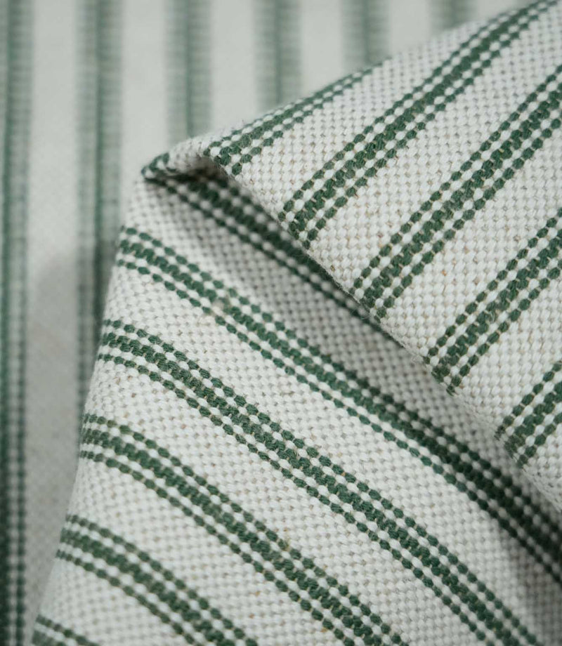 Detailed close-up of folded sap green ticking stripe fabric, highlighting the dark green woven stripes, natural cream background and textured weave.