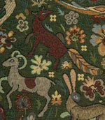 Close-up of a tapestry fabric with floral and animal patterns, including deer and goats.