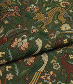 Close-up of intricately patterned tapestry fabric with animals and flowers on a green background