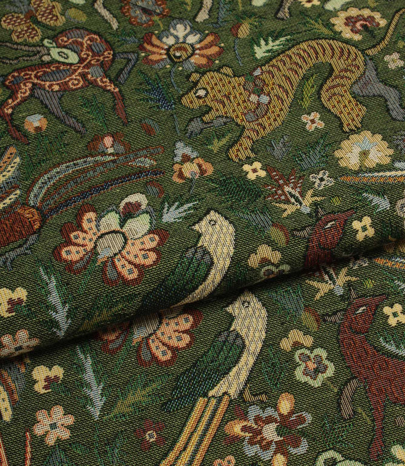 Close-up of intricately patterned tapestry fabric with animals and flowers on a green background