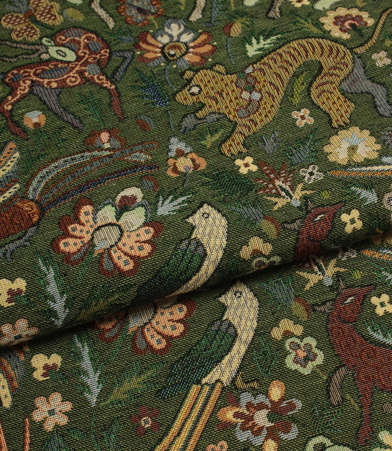 Close-up of intricately patterned tapestry fabric with animals and flowers on a green background