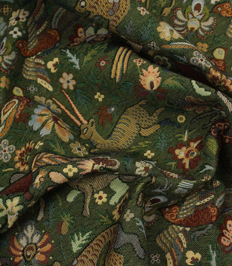 Close-up of a tapestry fabric with intricate pattern featuring animals and flowers on a green background