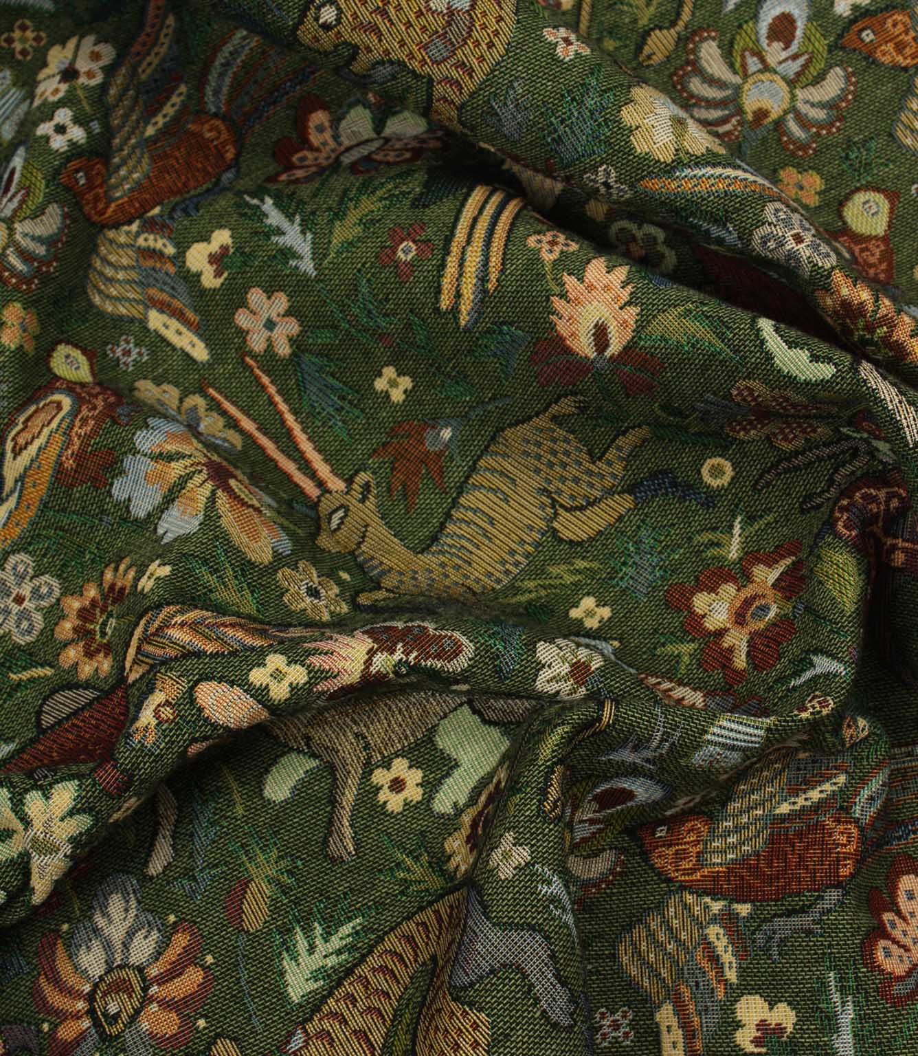 Close-up of a tapestry fabric with intricate pattern featuring animals and flowers on a green background