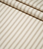 JF Ticking Beige striped fabric laid flat and folded, showing the evenly spaced beige ticking stripes and softly textured cream woven ground.
