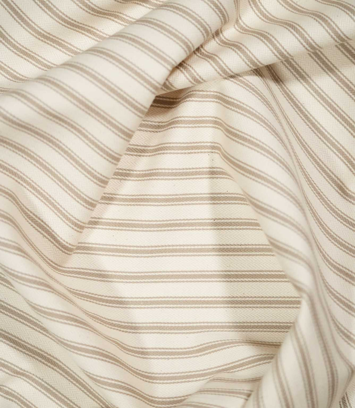 JF Ticking Beige fabric draped in soft folds, highlighting the classic beige ticking stripe design and subtle herringbone weave.