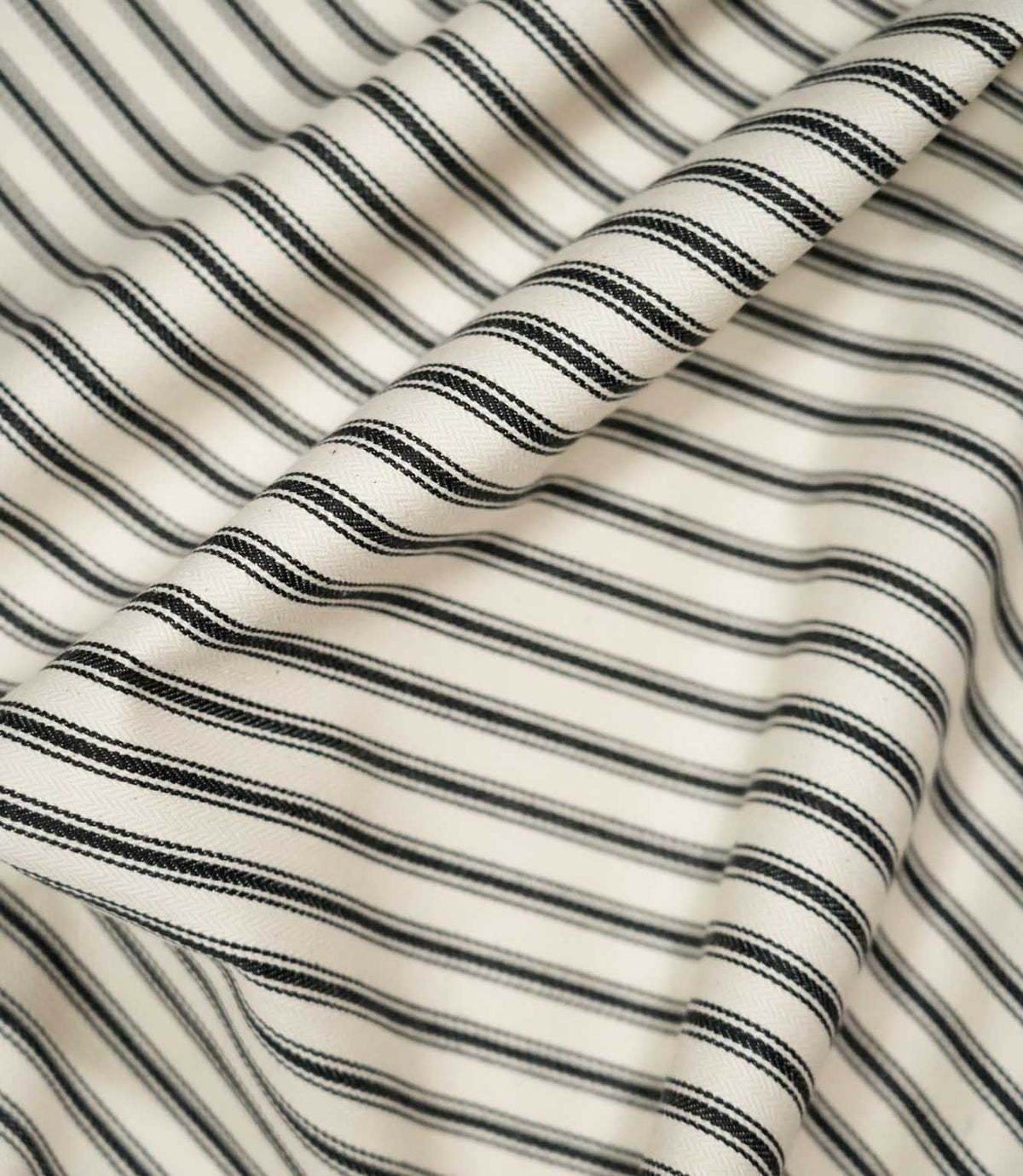 JF Ticking Black fabric draped in soft folds, highlighting the natural drape, classic black ticking stripes and subtle herringbone texture.