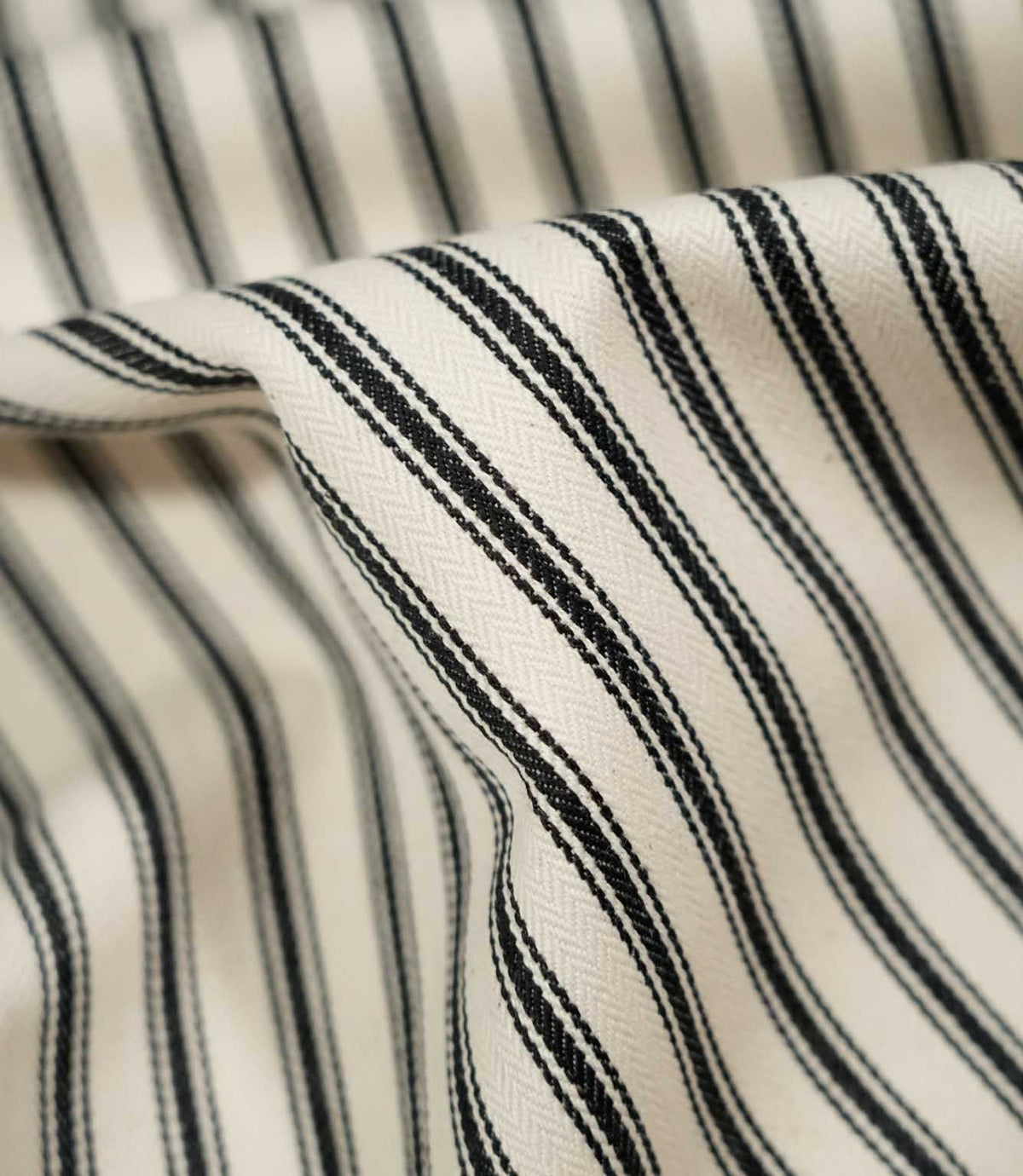 Detailed close-up of JF Ticking Black fabric showing the cream herringbone weave, textured black ticking stripes and soft natural drape.