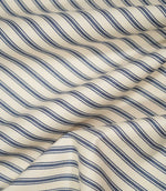 JF Ticking Blue fabric draped in soft folds, highlighting the natural drape, blue ticking stripe pattern and subtle herringbone texture.
