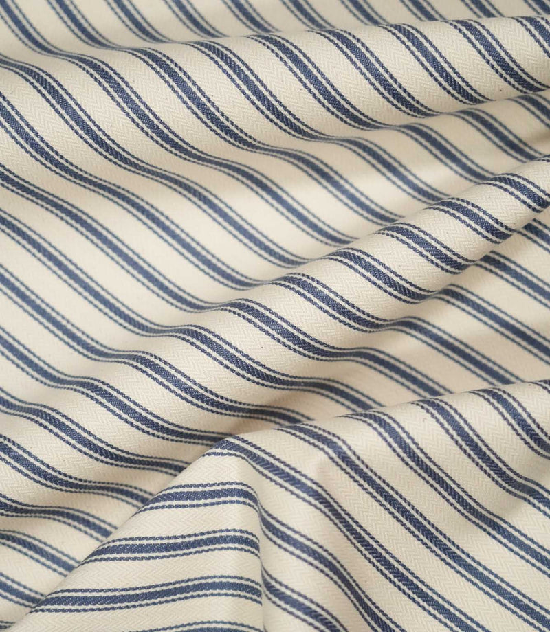 JF Ticking Blue fabric draped in soft folds, highlighting the natural drape, blue ticking stripe pattern and subtle herringbone texture.