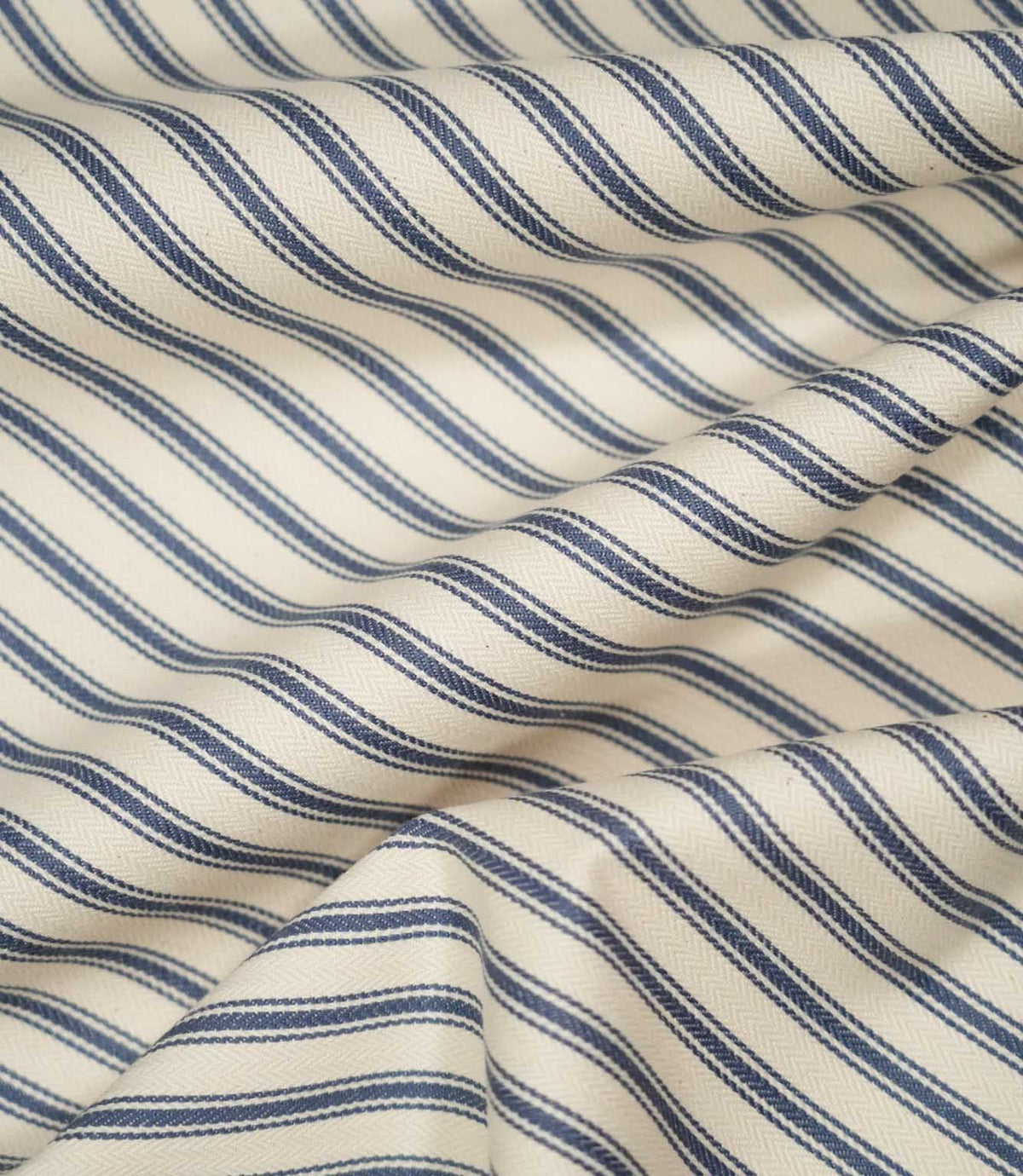 JF Ticking Blue fabric draped in soft folds, highlighting the natural drape, blue ticking stripe pattern and subtle herringbone texture.