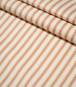 JF Ticking Burnt Orange striped fabric laid flat and neatly folded, showing the repeating ticking stripe design across a textured cream ground.