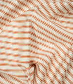 JF Ticking Burnt Orange fabric draped in soft folds, highlighting the natural drape, burnt orange ticking stripes and subtle herringbone texture.