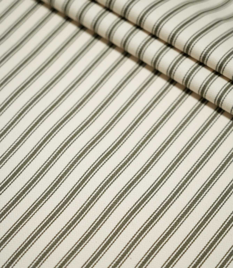 Layered folds of JF Ticking Forest striped fabric, displaying the repeating forest green ticking stripes and subtle ivory woven texture.