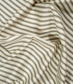 Draped JF Ticking Forest fabric in soft folds, showing the classic green and ivory ticking stripe design and natural woven texture.