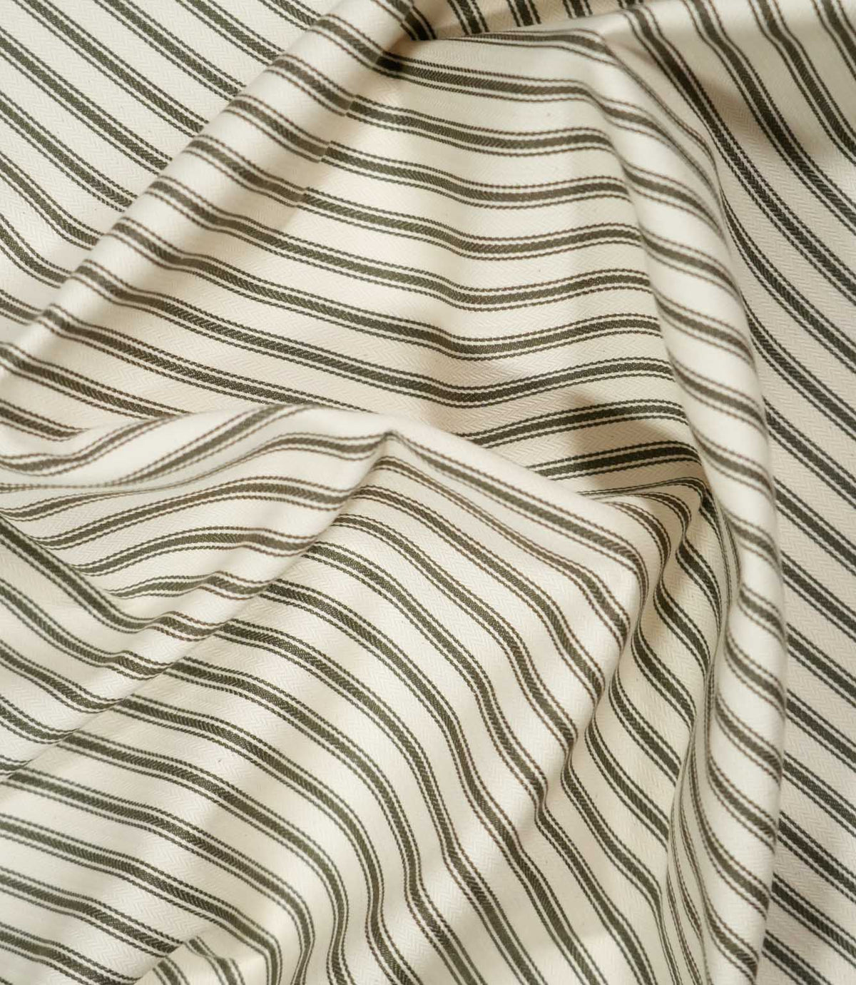 Draped JF Ticking Forest fabric in soft folds, showing the classic green and ivory ticking stripe design and natural woven texture.