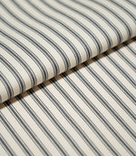 Close-up of folded JF Ticking Grey fabric showing the repeating charcoal grey ticking stripes and fine herringbone texture of the cream ground.