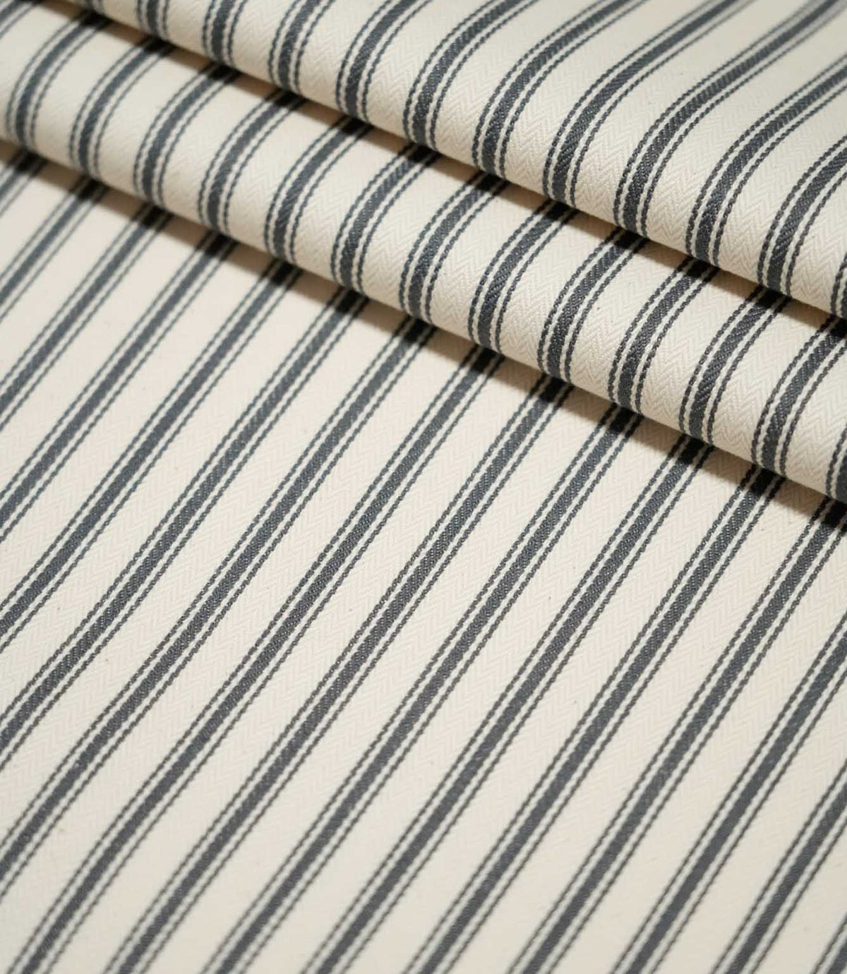 JF Ticking Grey striped fabric laid flat and neatly folded, showing the repeating grey ticking stripe pattern and textured cream weave.