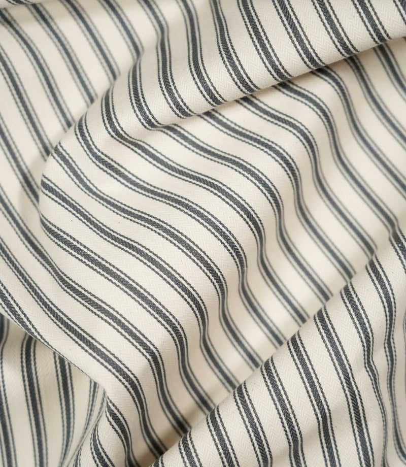 JF Ticking Grey fabric draped in soft folds, highlighting the natural drape, charcoal grey ticking stripes and subtle woven herringbone texture.
