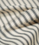 Detailed close-up of JF Ticking Grey fabric showing the charcoal grey woven ticking stripes, warm cream background and fine herringbone texture.