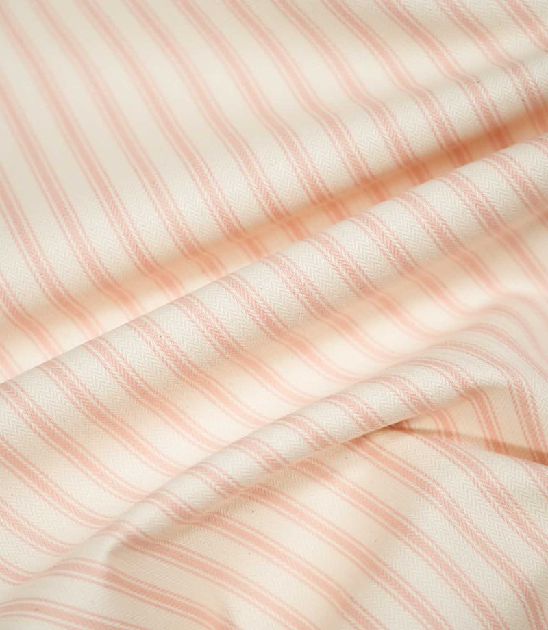JF Ticking Pink fabric draped in soft folds, highlighting its natural drape, blush pink ticking stripe pattern and textured cream weave.