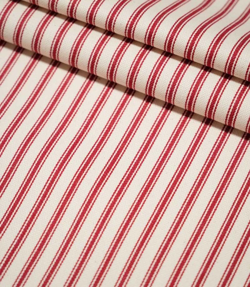 JF Ticking Red striped fabric arranged in neat folds, showing the bold repeating red stripes and textured cream herringbone weave.