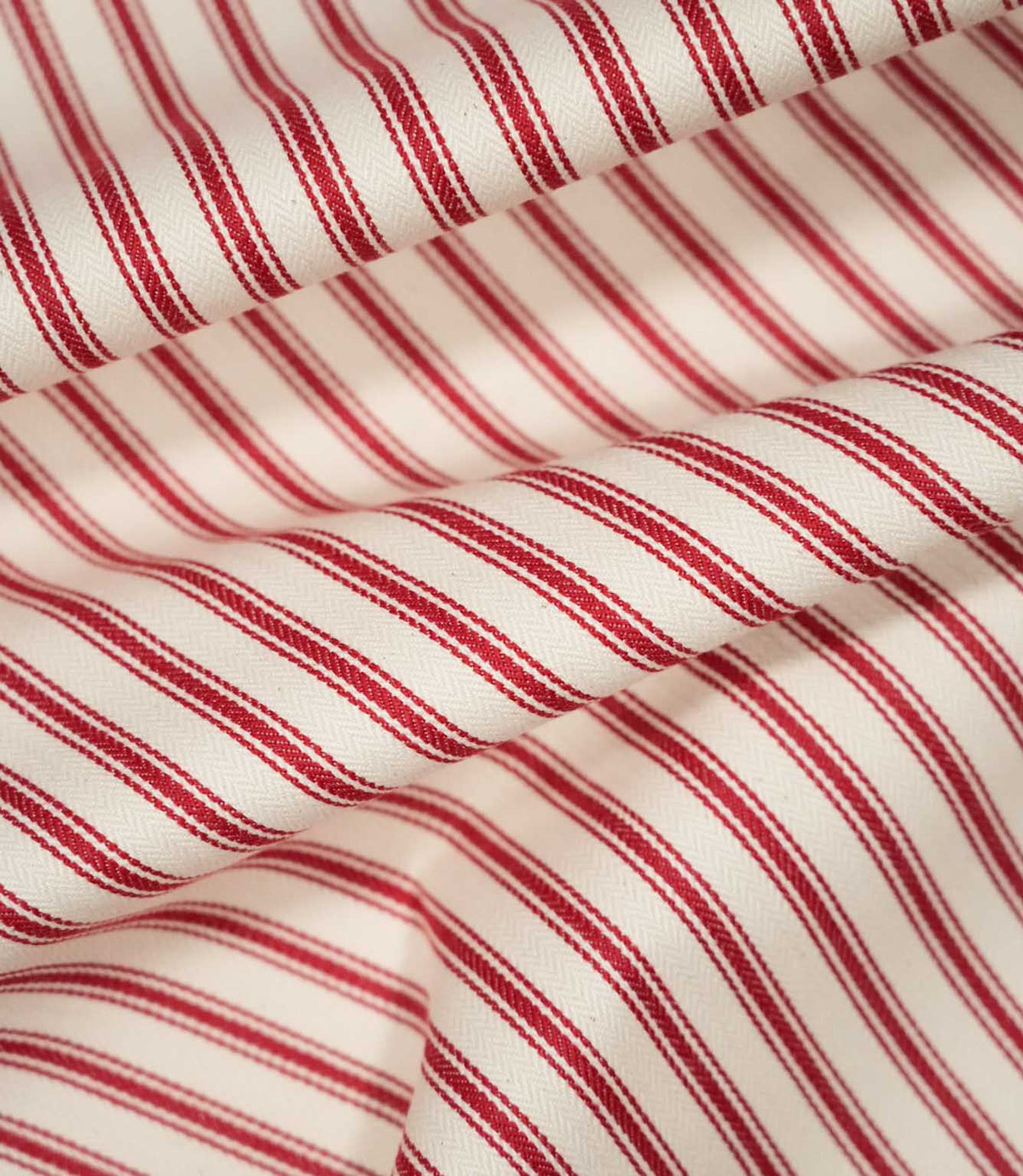 JF Ticking Red fabric draped in soft folds, highlighting the classic red ticking stripe design, woven texture and natural drape of the fabric.