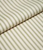 Close-up of folded JF Ticking Sap Green fabric showing the repeating olive green ticking stripes and fine woven herringbone texture of the cream background.