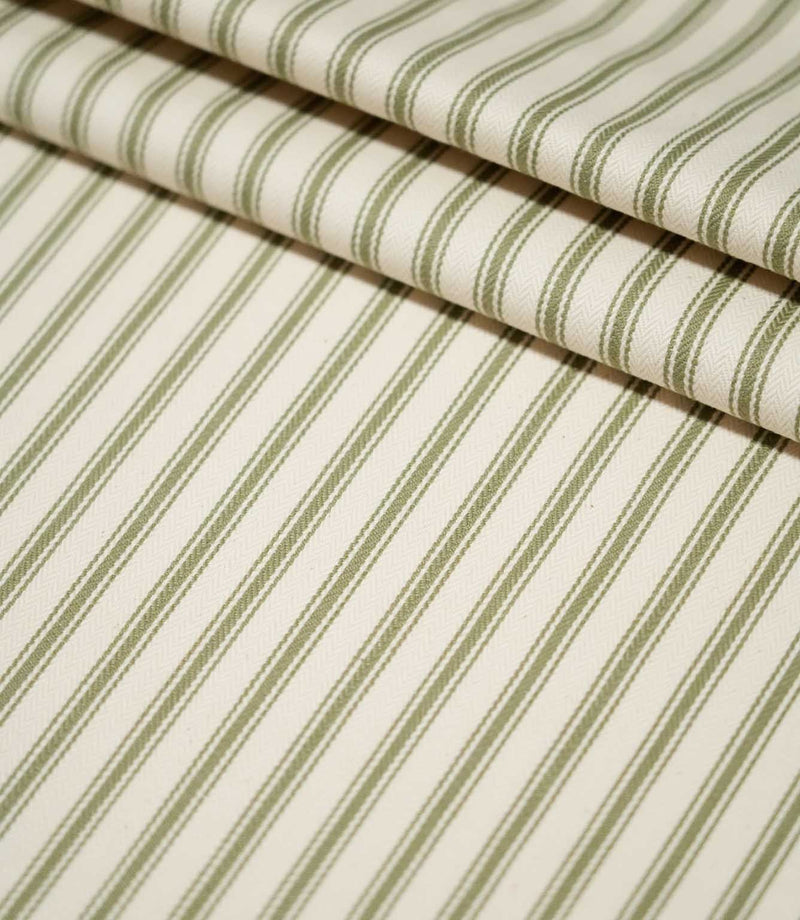 JF Ticking Sap Green striped fabric arranged in neat folds, showing the evenly spaced olive green stripes and textured cream woven ground.
