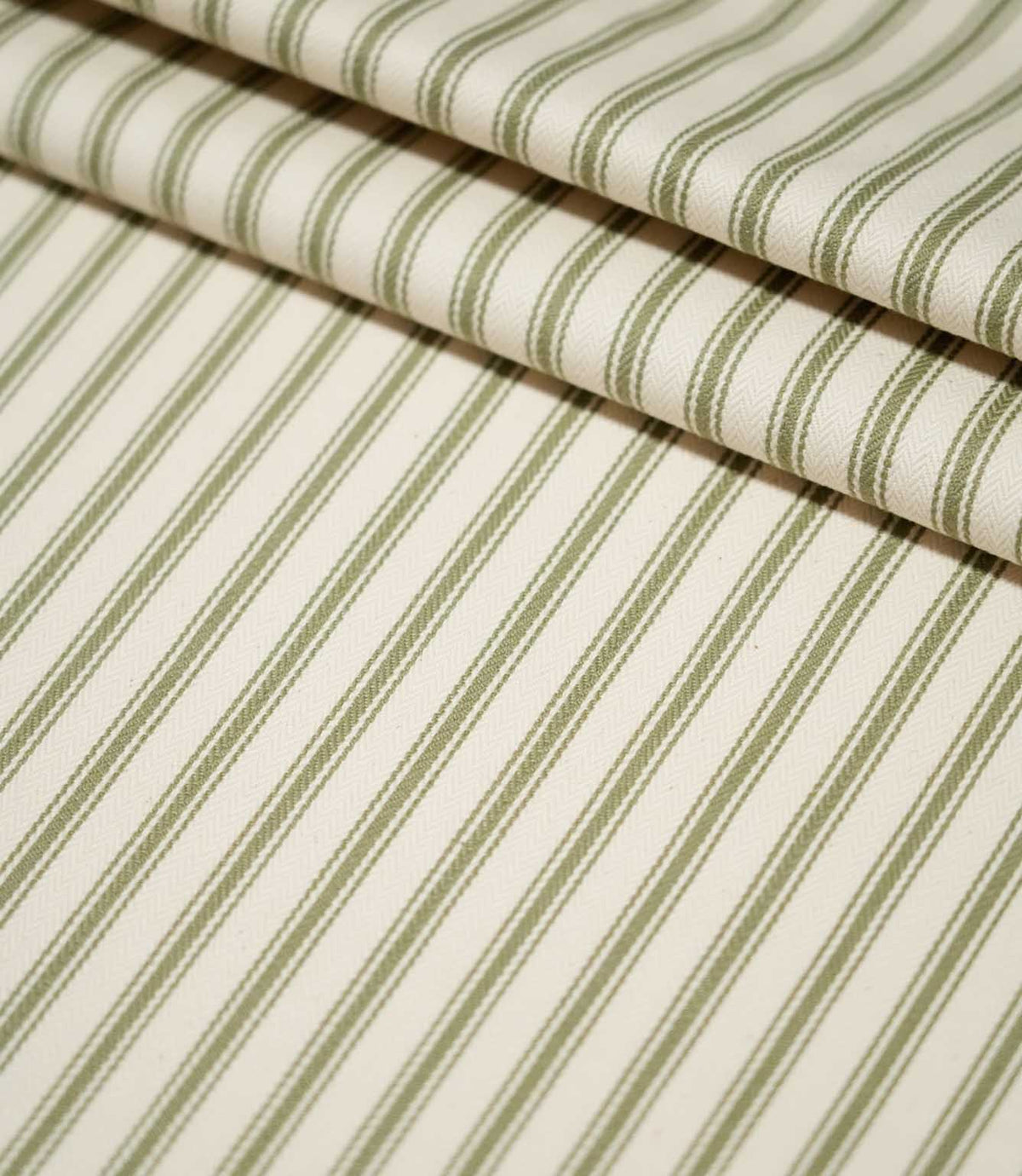 JF Ticking Sap Green striped fabric arranged in neat folds, showing the evenly spaced olive green stripes and textured cream woven ground.